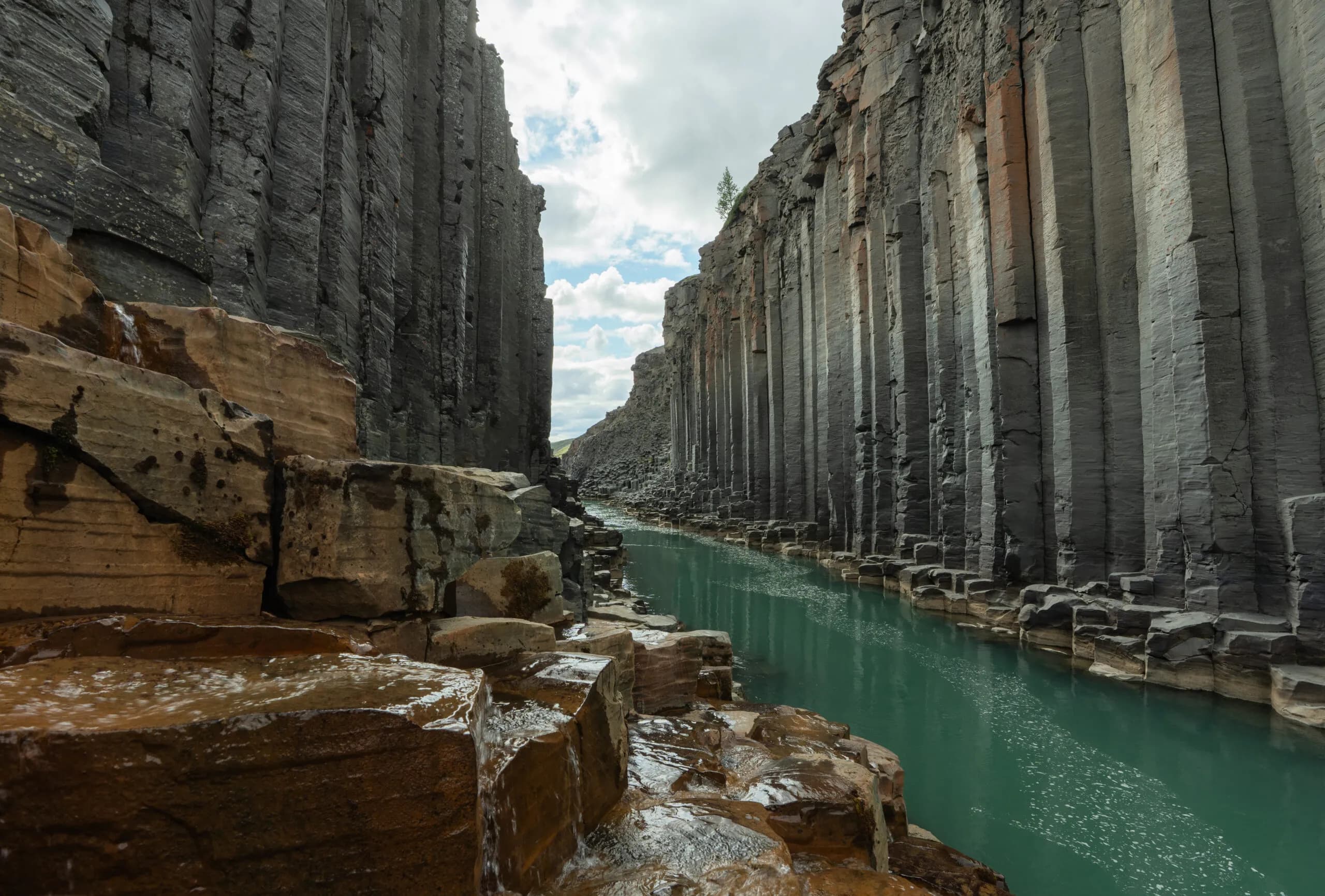 Vista a ras de río del cañón de Stuðlagil, con las columnas de basalto y el agua turquesa, lado este, Islandia