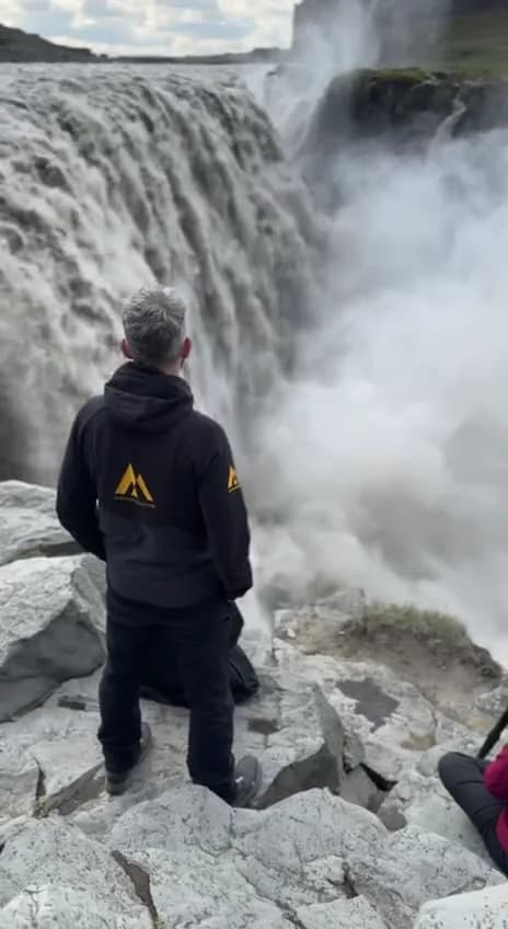 Una persona frente a la cascada Dettifoss envuelta en la nube de spray, norte de Islandia