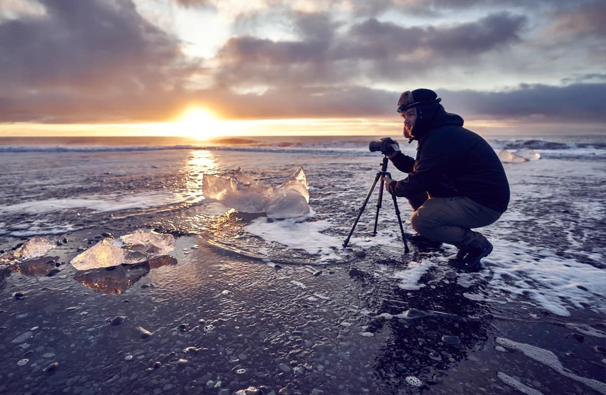 Fotógrafo con trípode fotografiando el hielo al amanecer en la Playa de los Diamantes