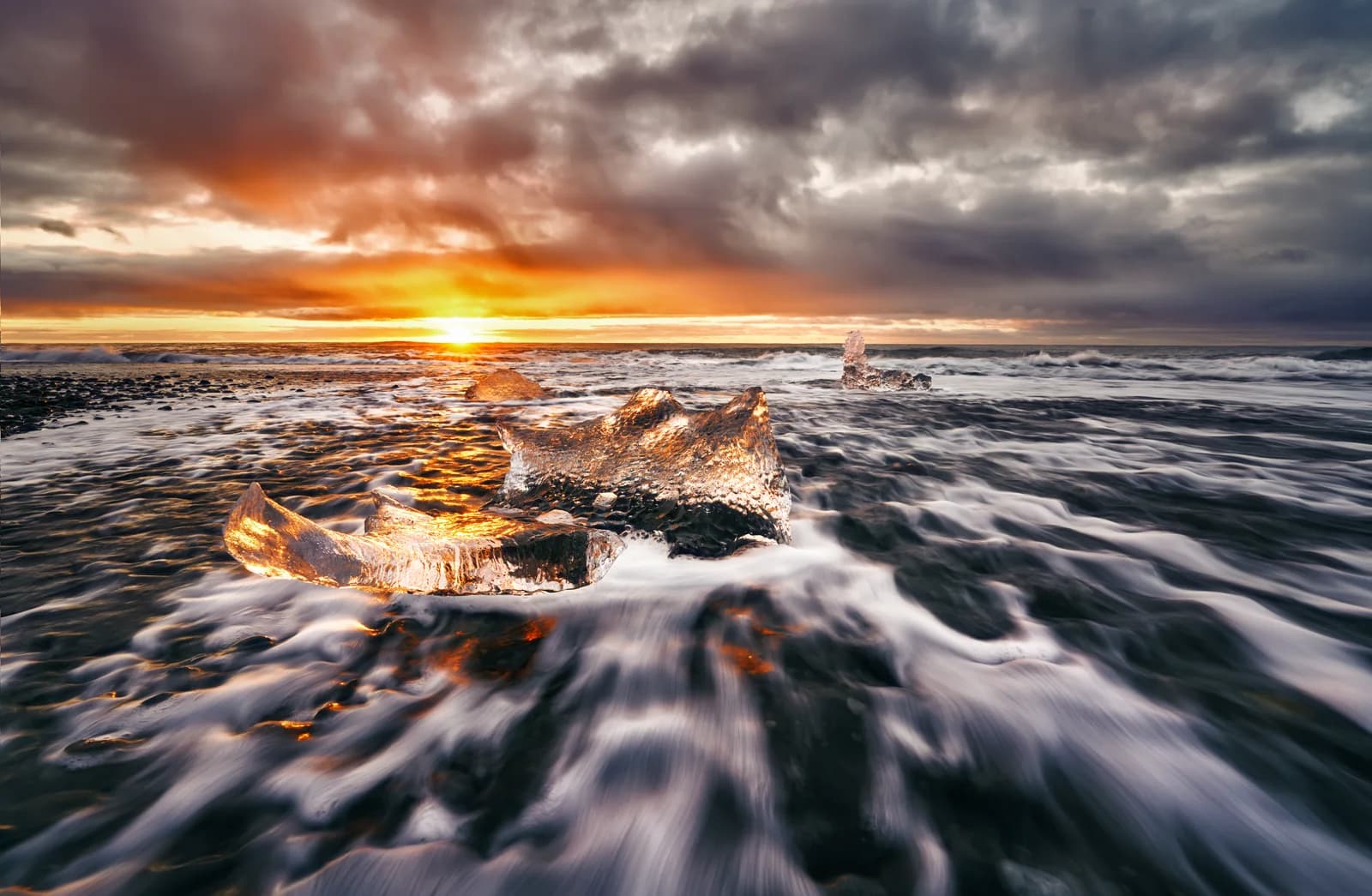 Amanecer en Diamond Beach con icebergs sobre la arena negra, sur de Islandia
