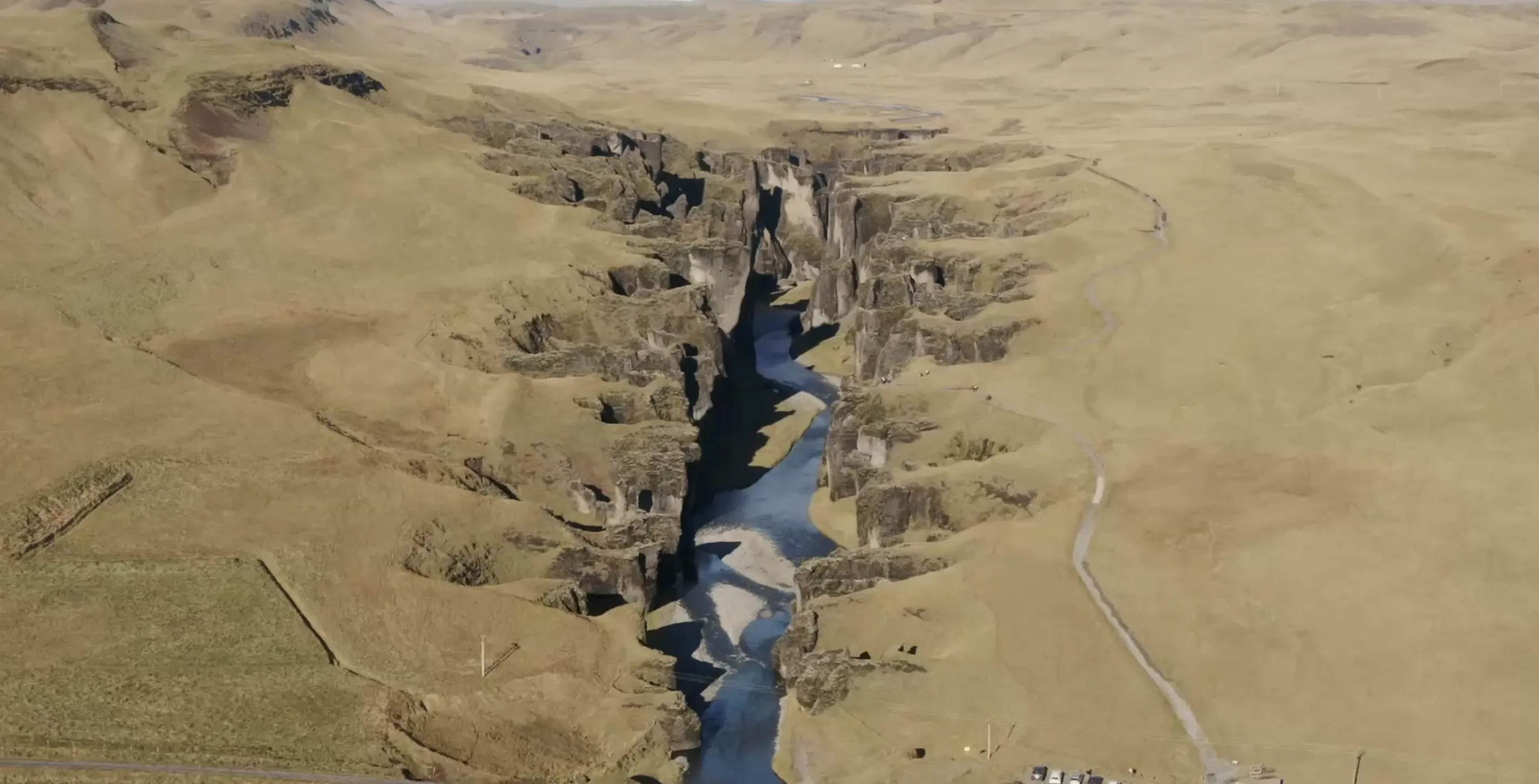 Vista aérea panorámica del cañón de Fjaðrárgljúfur con el sendero y el parking al fondo, sur de Islandia