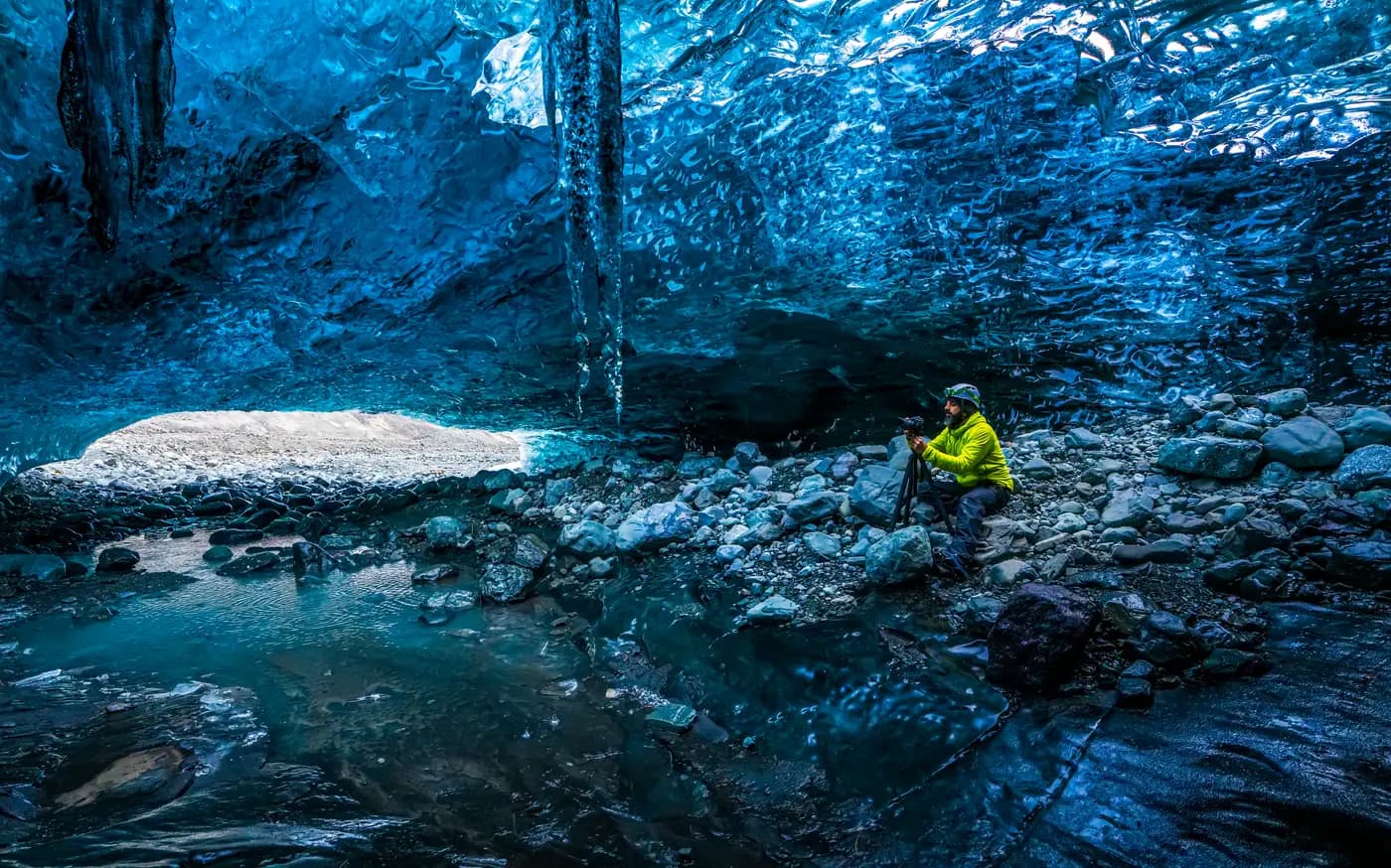 Persona en el interior de una cueva de hielo en el glaciar Vatnajökull, Islandia, mostrando la escala real del hielo azul