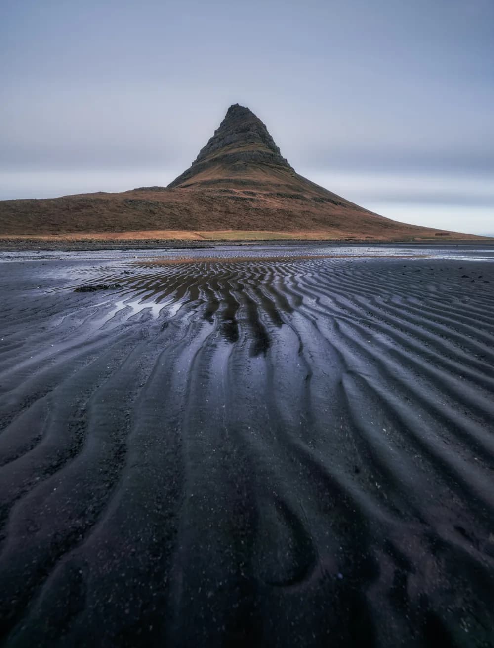 Montaña Kirkjufell reflejada en la playa de arena negra en bajamar, Islandia