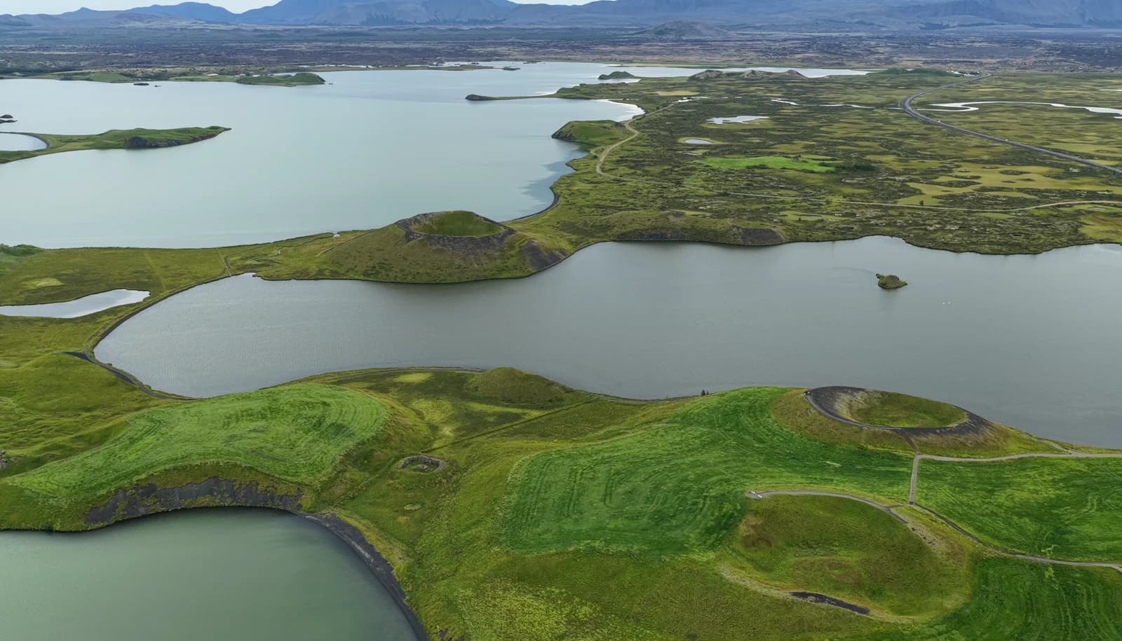 Vista aérea del lago Mývatn con sus pseudocráteres y campos verdes, norte de Islandia