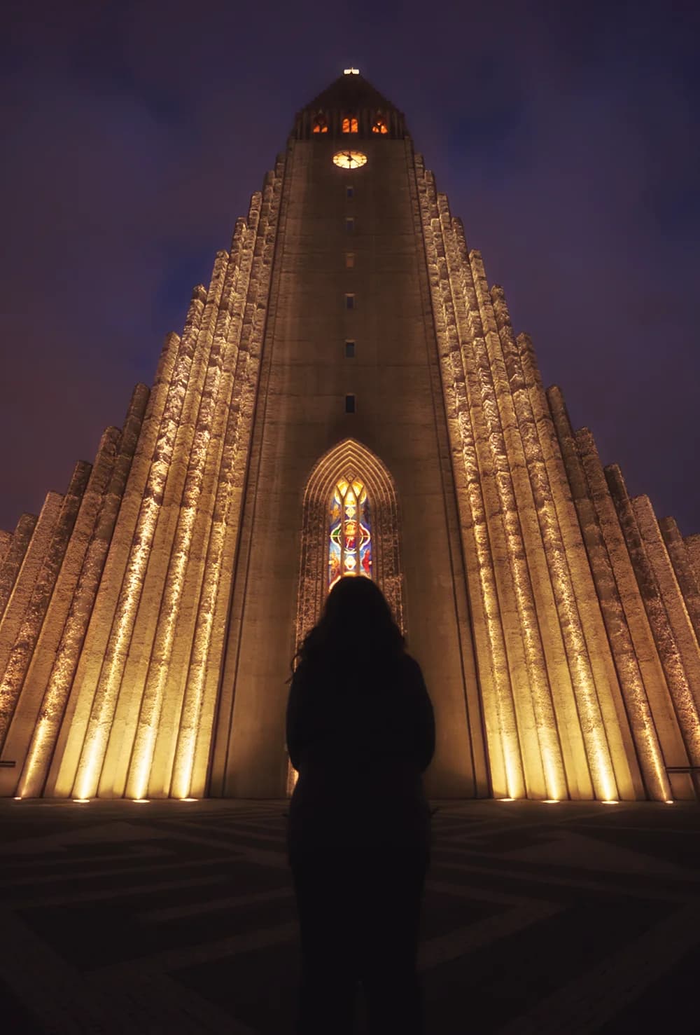 Silueta frente a la iglesia Hallgrímskirkja iluminada de noche en Reikiavik