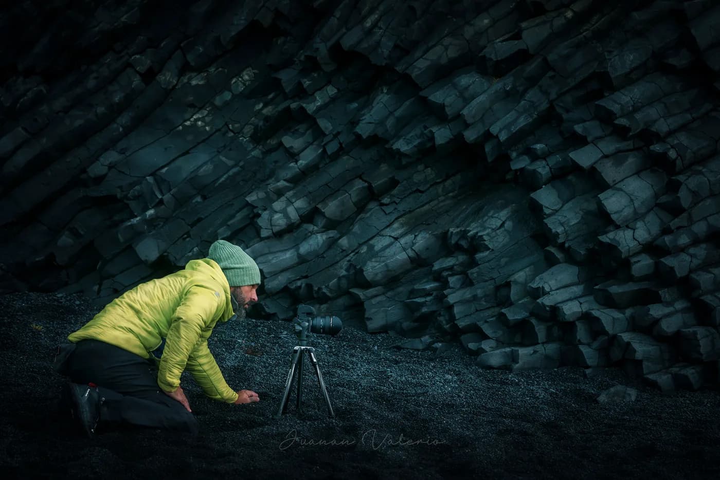 Fotógrafo con trípode explorando ángulos entre las columnas de basalto de la cueva de Reynisfjara, sur de Islandia