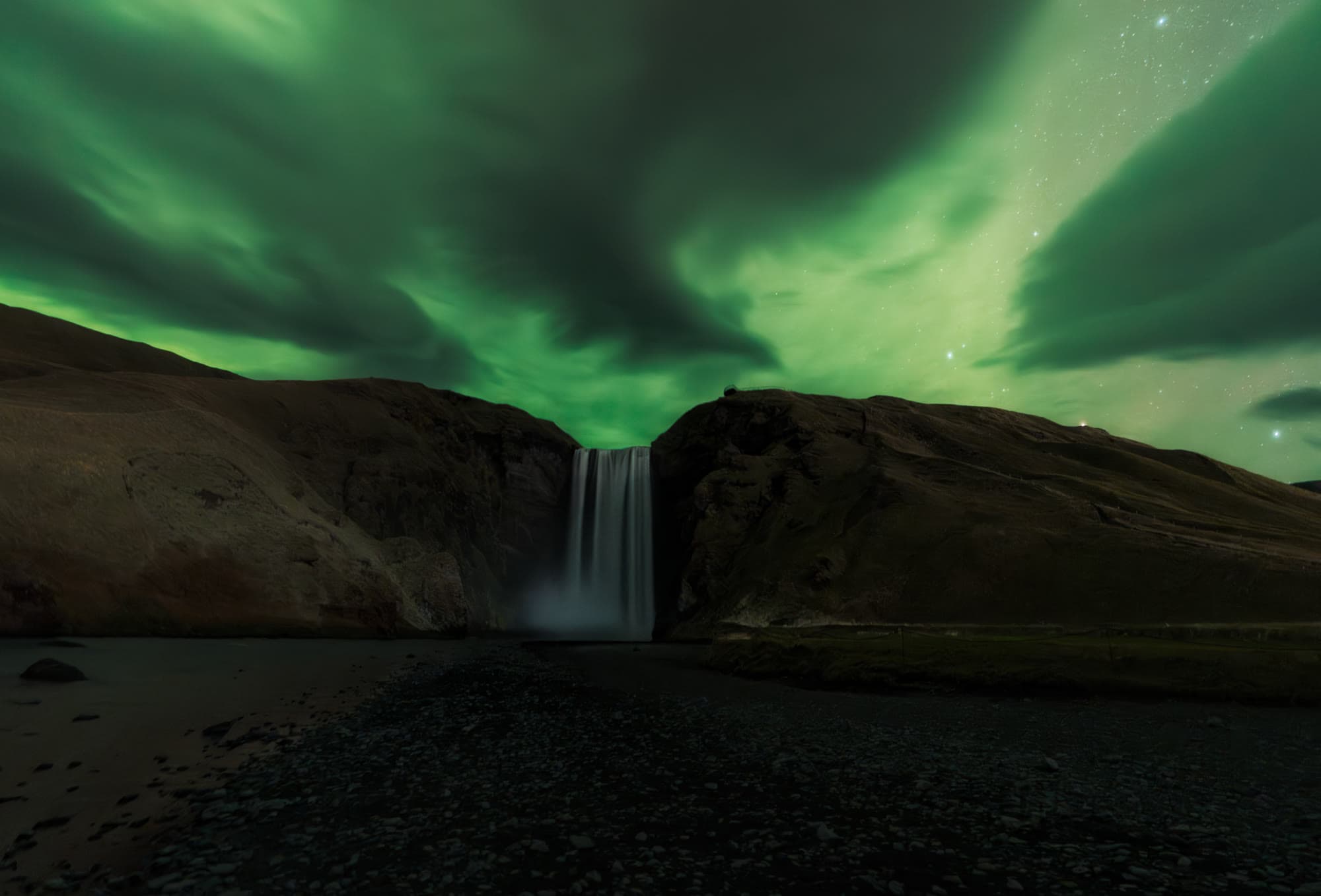 Aurora boreal sobre la cascada Skógafoss en otoño, sur de Islandia, fotografía nocturna