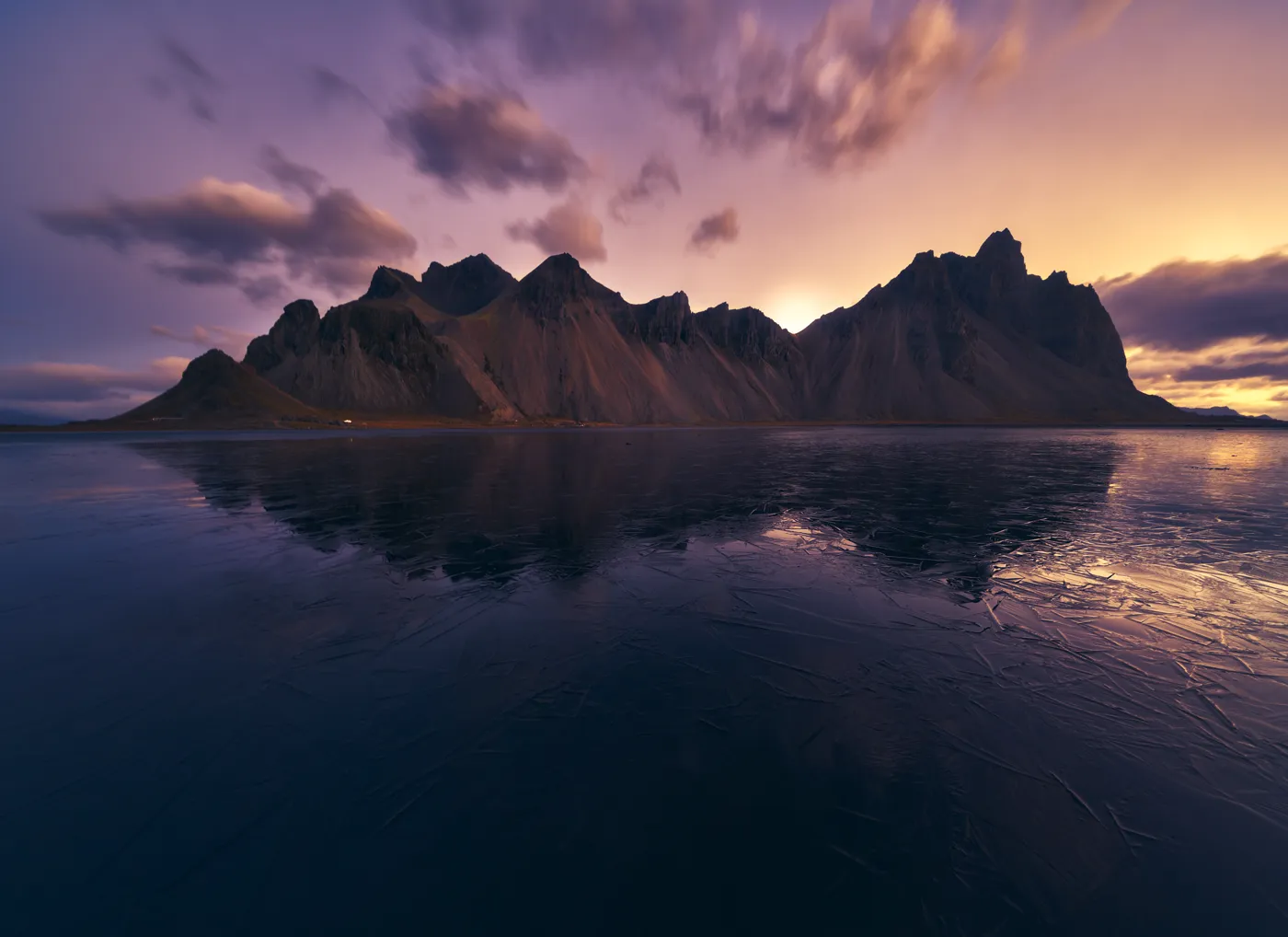 Monte Vestrahorn reflejado en hielo al atardecer con cielo morado y dorado, Stokksnes