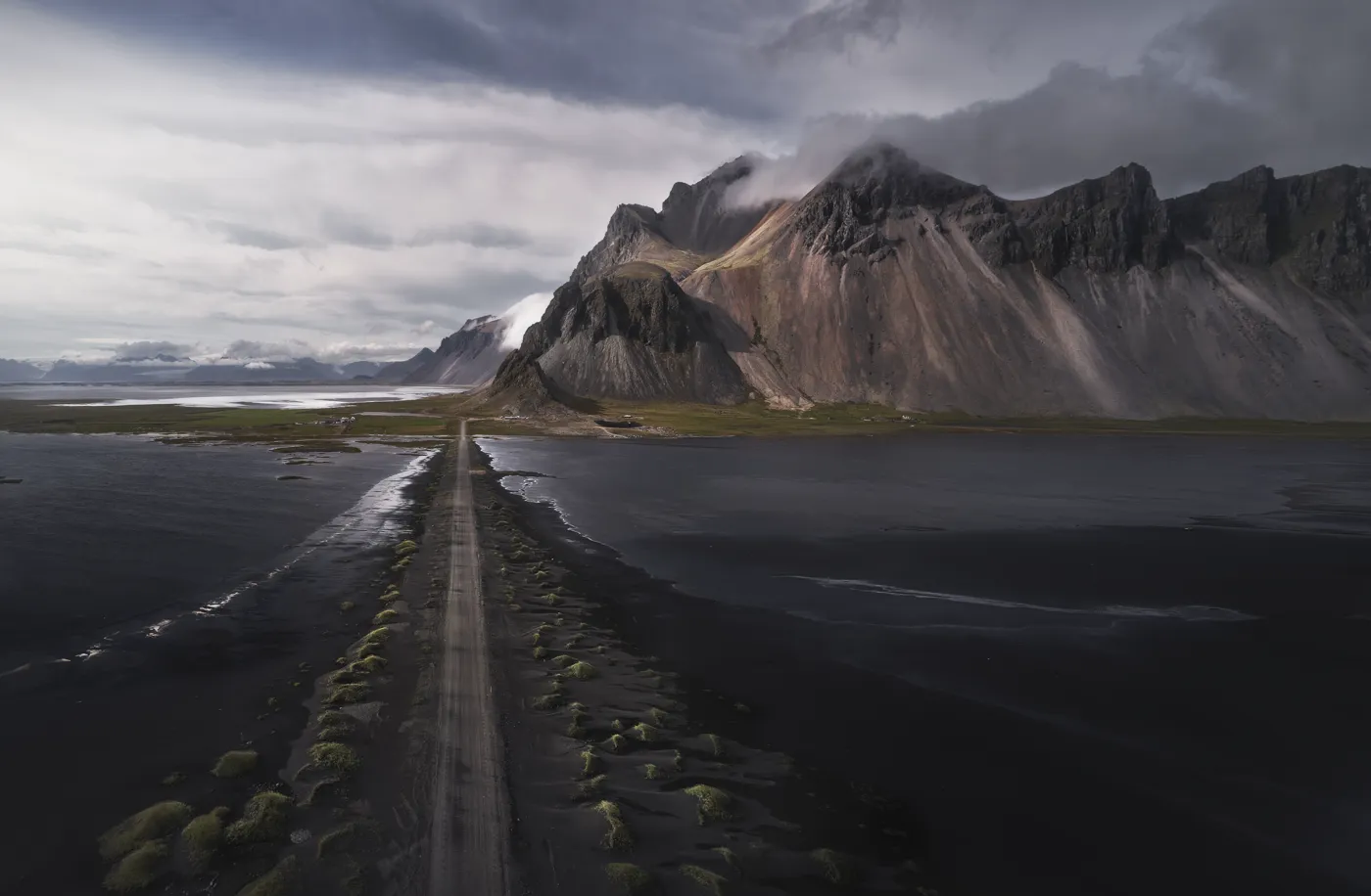 Vista aérea de la carretera de acceso hacia el monte Vestrahorn entre nubes bajas, Stokksnes