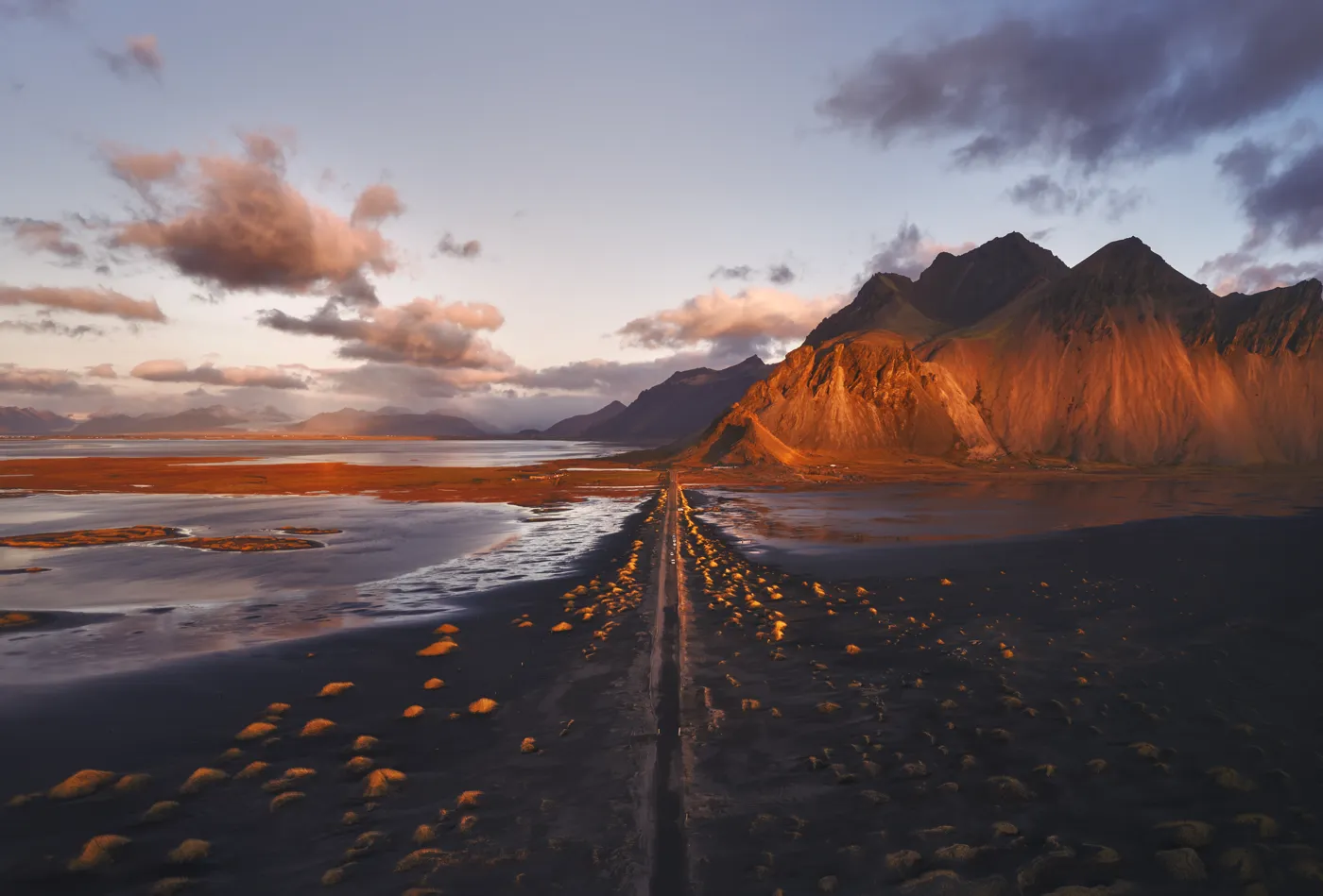 Vista aérea al amanecer de la carretera hacia el monte Vestrahorn con luz dorada, Stokksnes