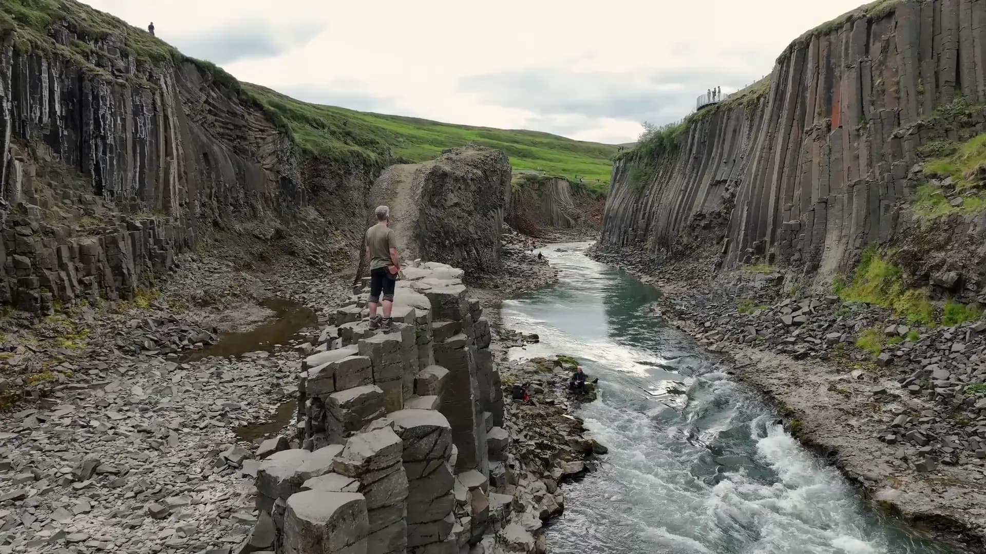 Vista aérea de una persona sobre las columnas de basalto del cañón de Stuðlagil, con el mirador del lado oeste al fondo