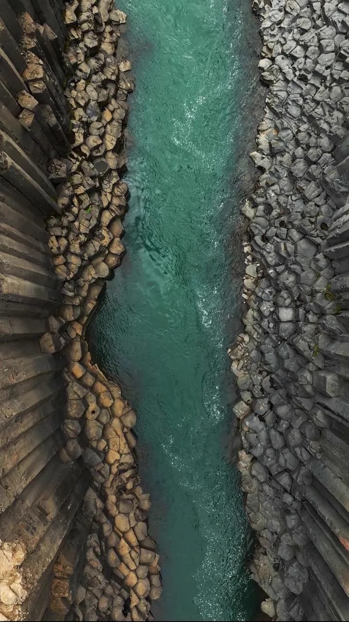 Vista cenital del agua turquesa entre las columnas de basalto del cañón de Stuðlagil, Islandia