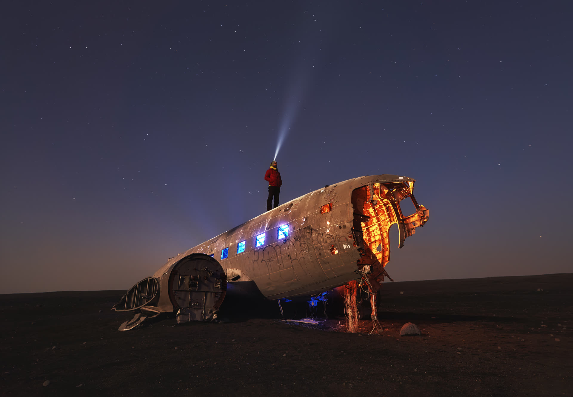 Interior del avión estrellado de Islandia de noche con modelo mirando al cielo — luz cálida en cabina y fría en fuselaje