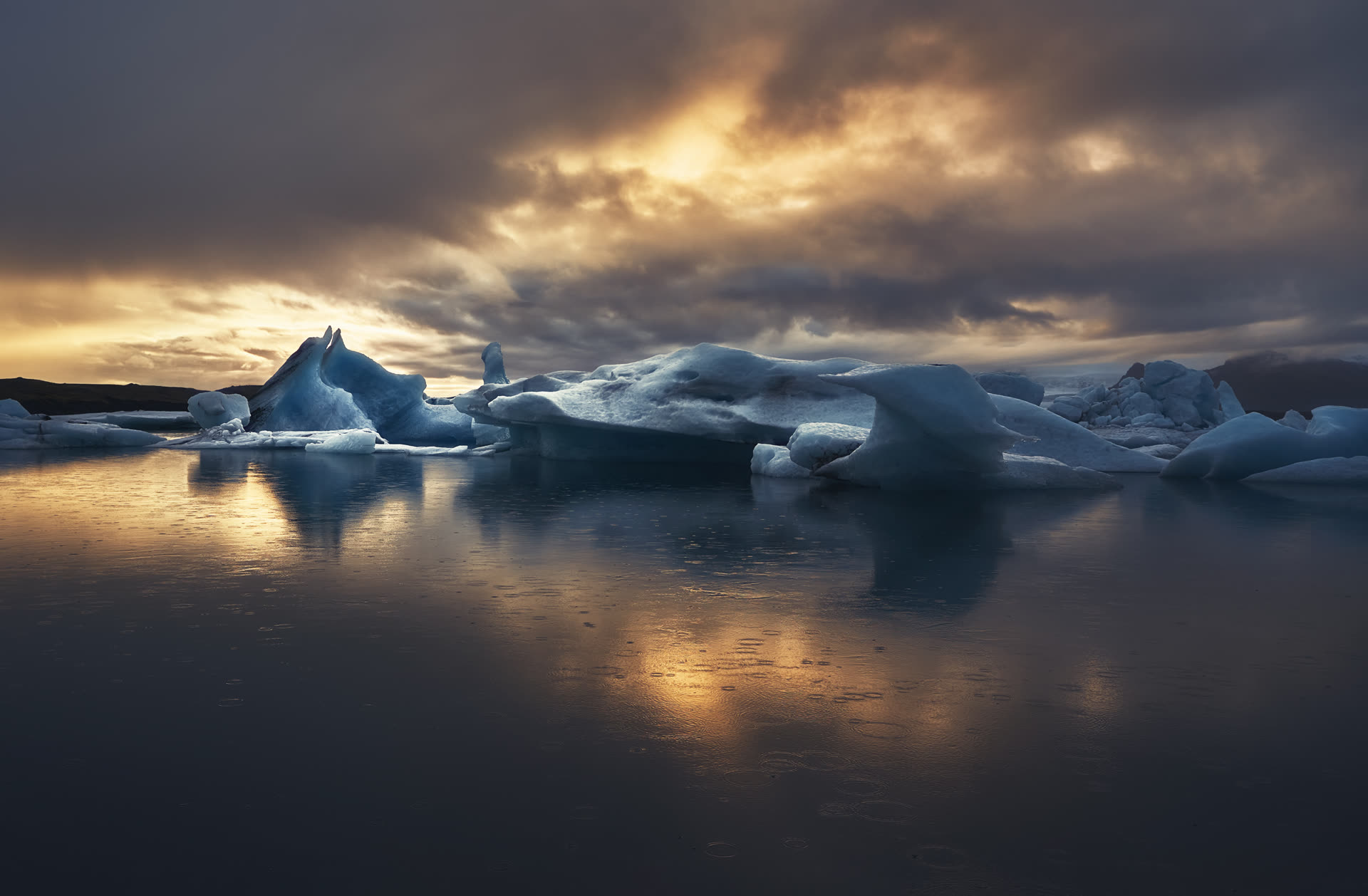 Atardecer con lluvia sobre la laguna glaciar de Jökulsárlón, Islandia — luz dorada sobre el agua