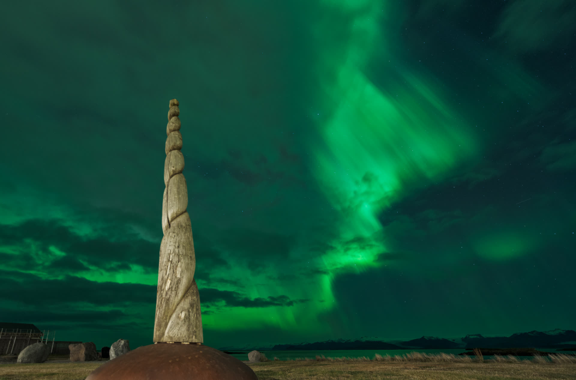 Aurora boreal en Höfn con obelisco unicornio, este de Islandia — cielo verde de auroras sobre el pueblo