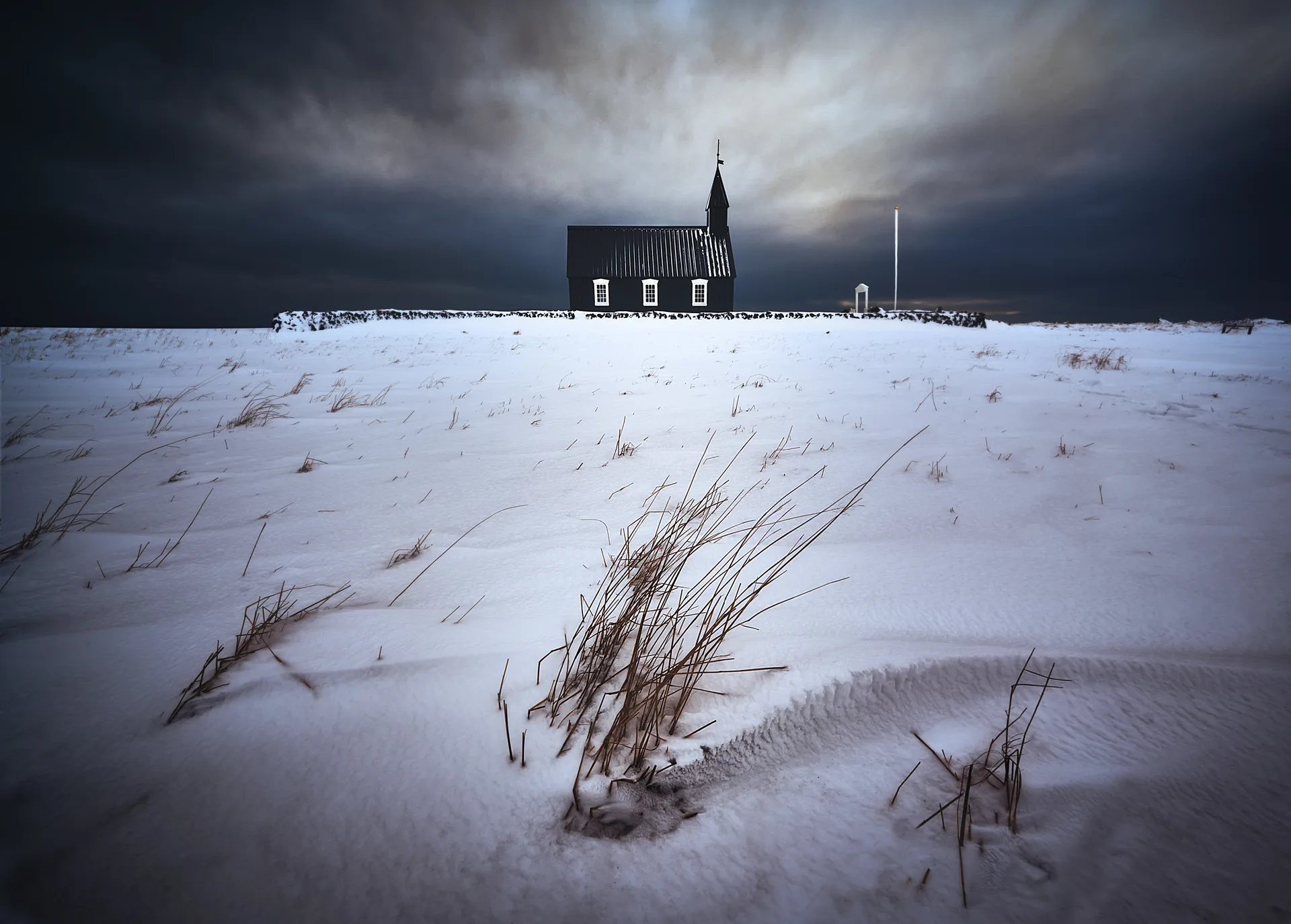 Iglesia negra de Búðir en invierno sobre manto de nieve, Snæfellsnes, Islandia — montañas y nubes como telón de fondo