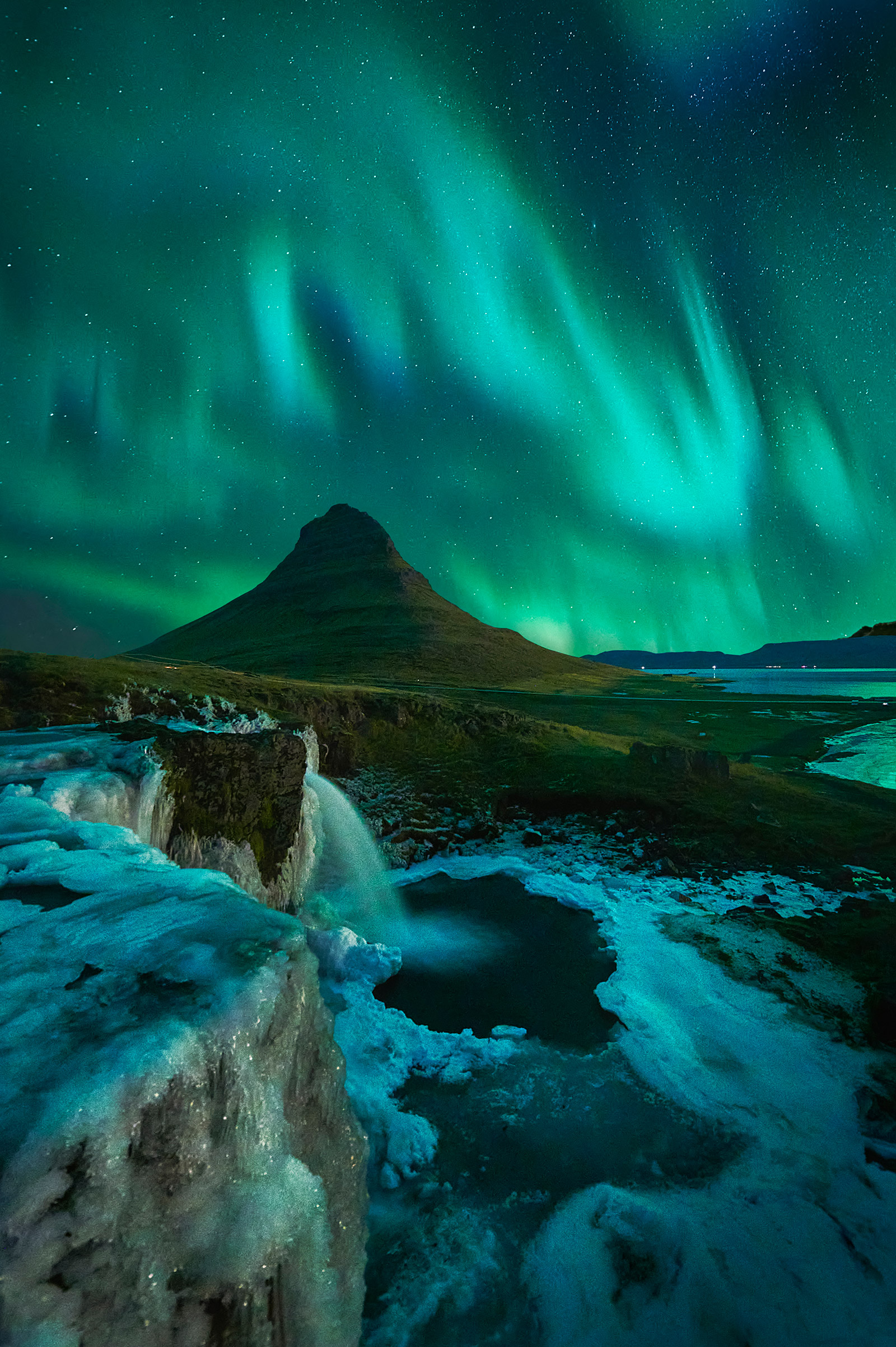 Auroras boreales sobre la montaña Kirkjufell y la cascada Kirkjufellsfoss en Islandia