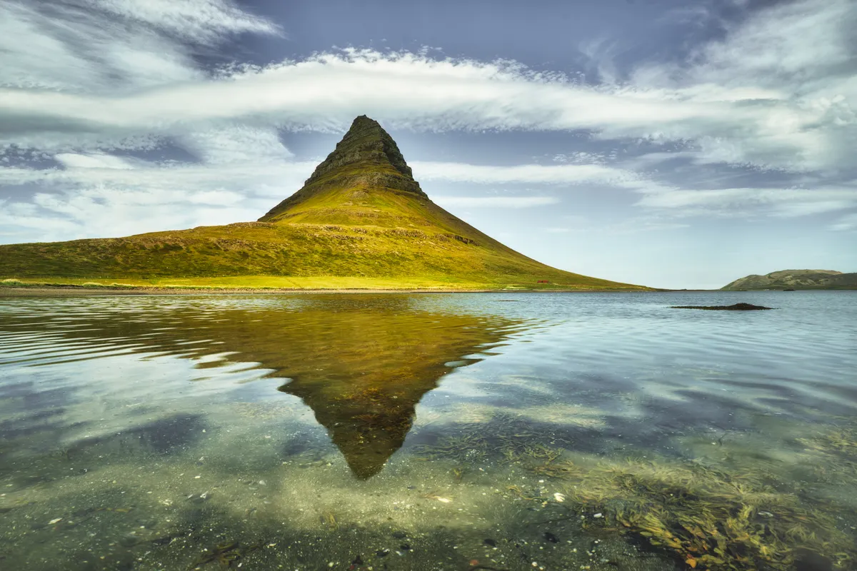 Monte Kirkjufell en verano con vegetación verde y buen tiempo, península de Snæfellsnes, Islandia