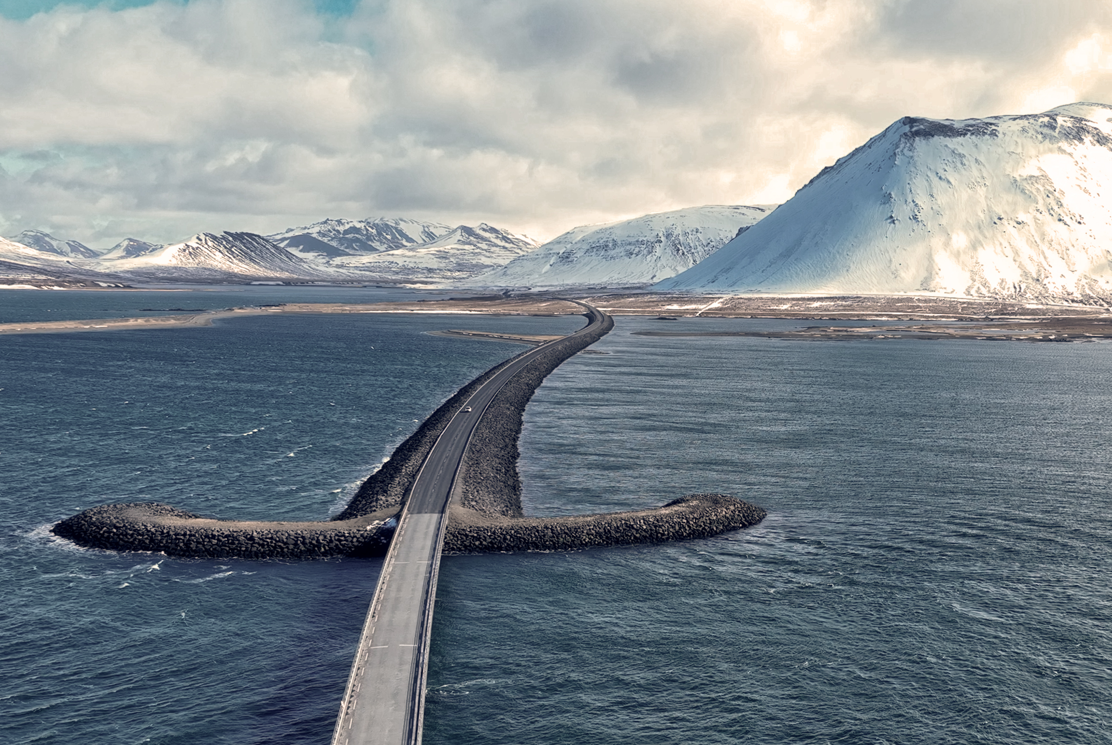 Puente en Snæfellsnes con montañas nevadas, Islandia Puente y carretera sobre el mar con montañas nevadas al fondo en la península de Snæfellsnes, Islandia