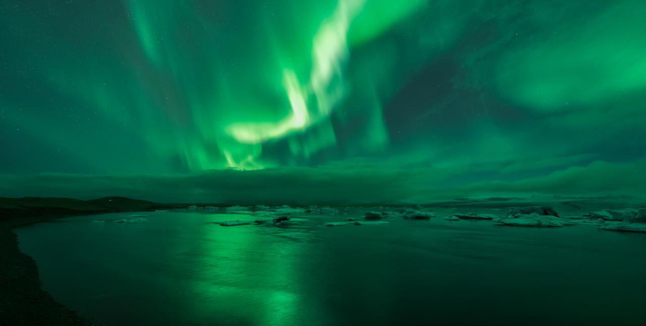 Auroras boreales sobre Jökulsárlón con reflejo espectacular en el agua de la laguna glaciar