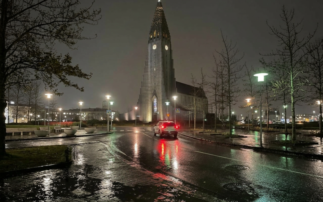 Calle de Reikiavik de noche tras la lluvia con la Hallgrímskirkja al fondo y coche circulando