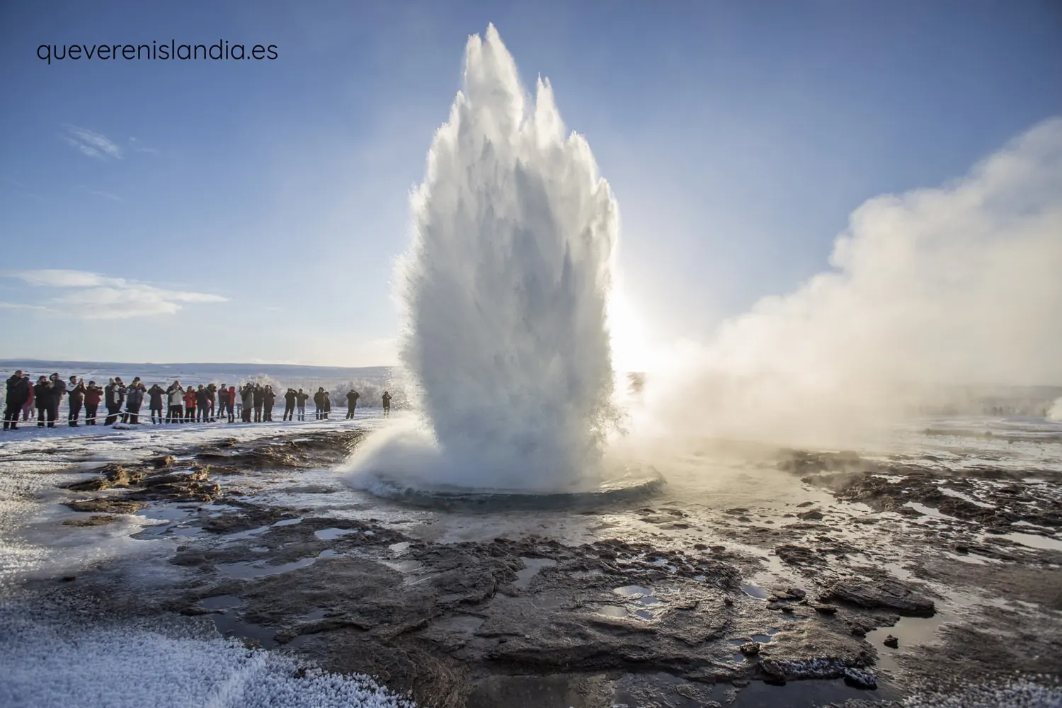 Erupción del géiser Strokkur con visitantes al fondo en el Círculo Dorado de Islandia