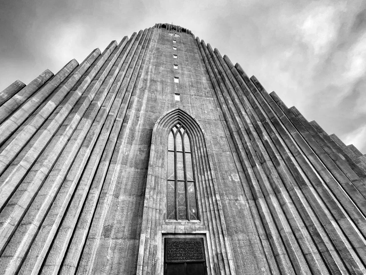 Vista contrapicada en blanco y negro de la torre de la Hallgrímskirkja con cielo nuboso, Reikiavik