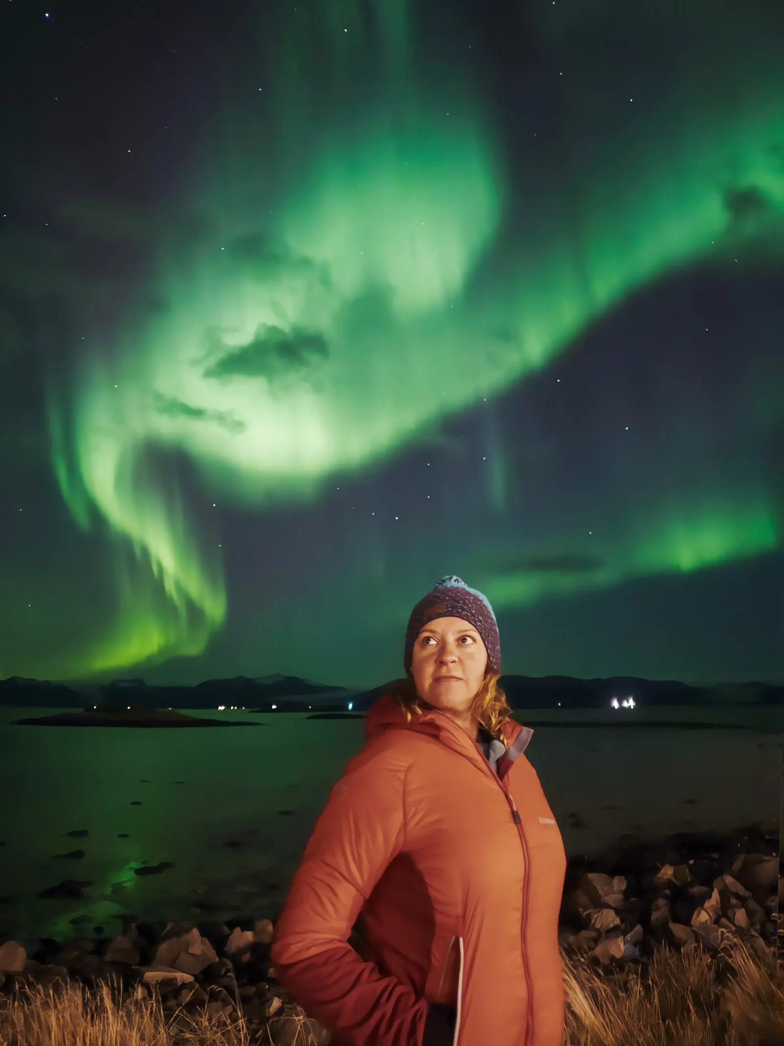 Mujer con ropa de abrigo viendo auroras boreales en Islandia