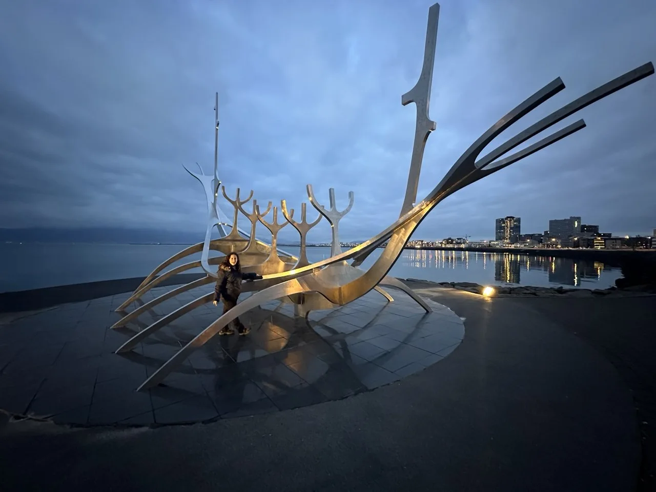 Sólfar Sun Voyager nocturno con reflejos en Reikiavik Escultura Sólfar Sun Voyager de noche con reflejos de las luces de Reikiavik en el agua