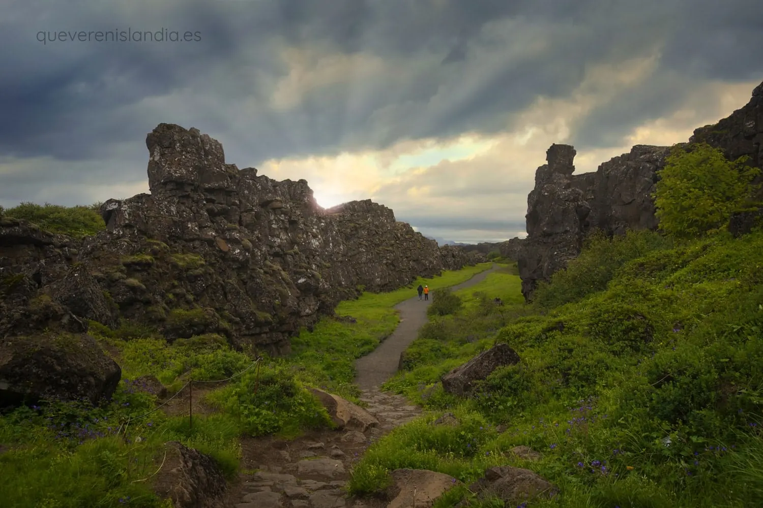 Personas paseando por la grieta tectónica de Þingvellir con vegetación verde al atardecer