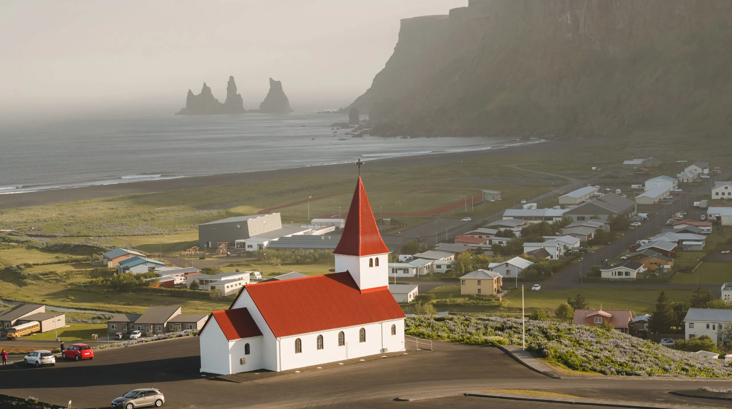 Iglesia de Vík con el pueblo y la playa negra al fondo en el sur de Islandia