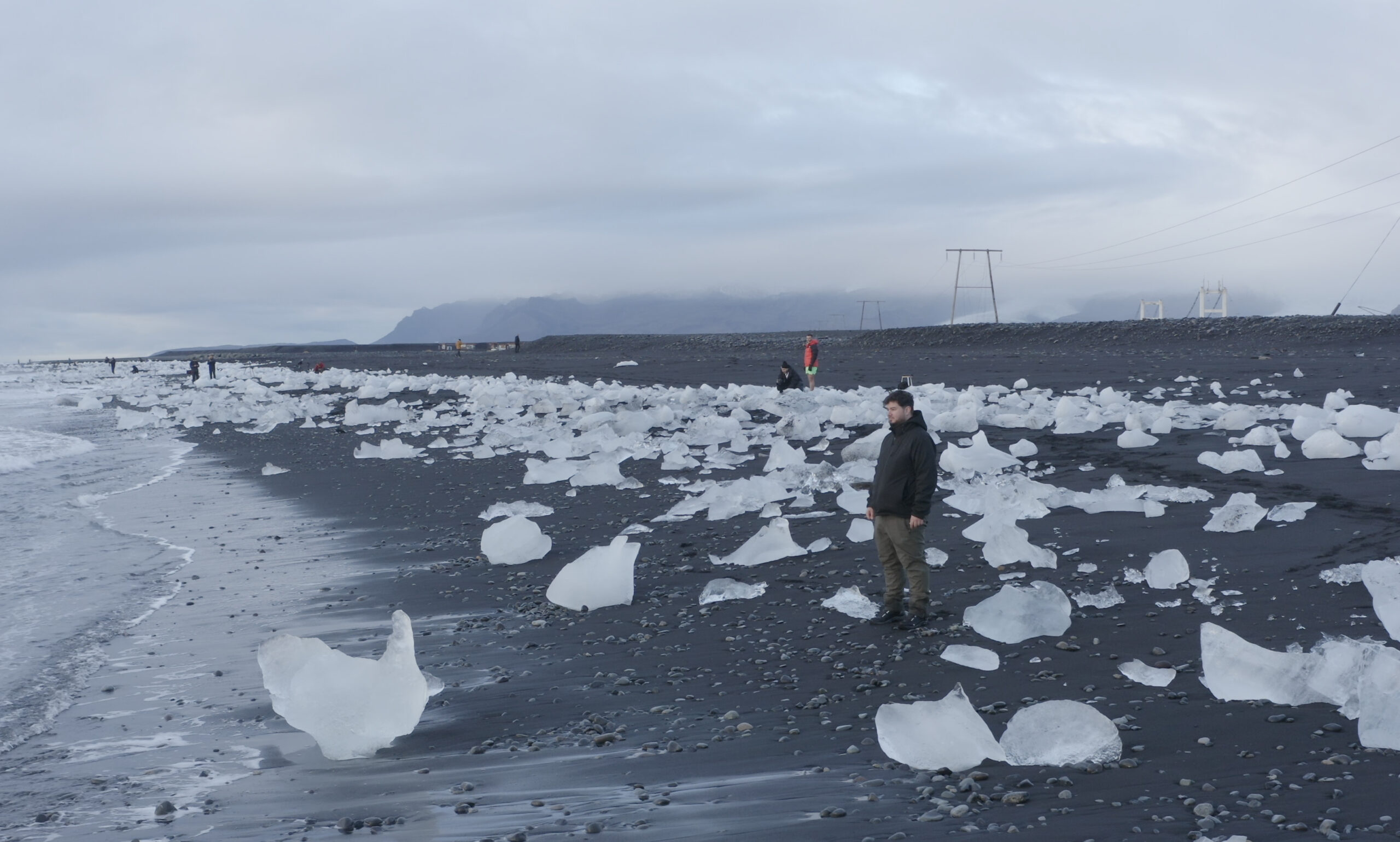 Persona entre trozos de hielo glaciar en la playa de los diamantes de Islandia mostrando su tamaño real