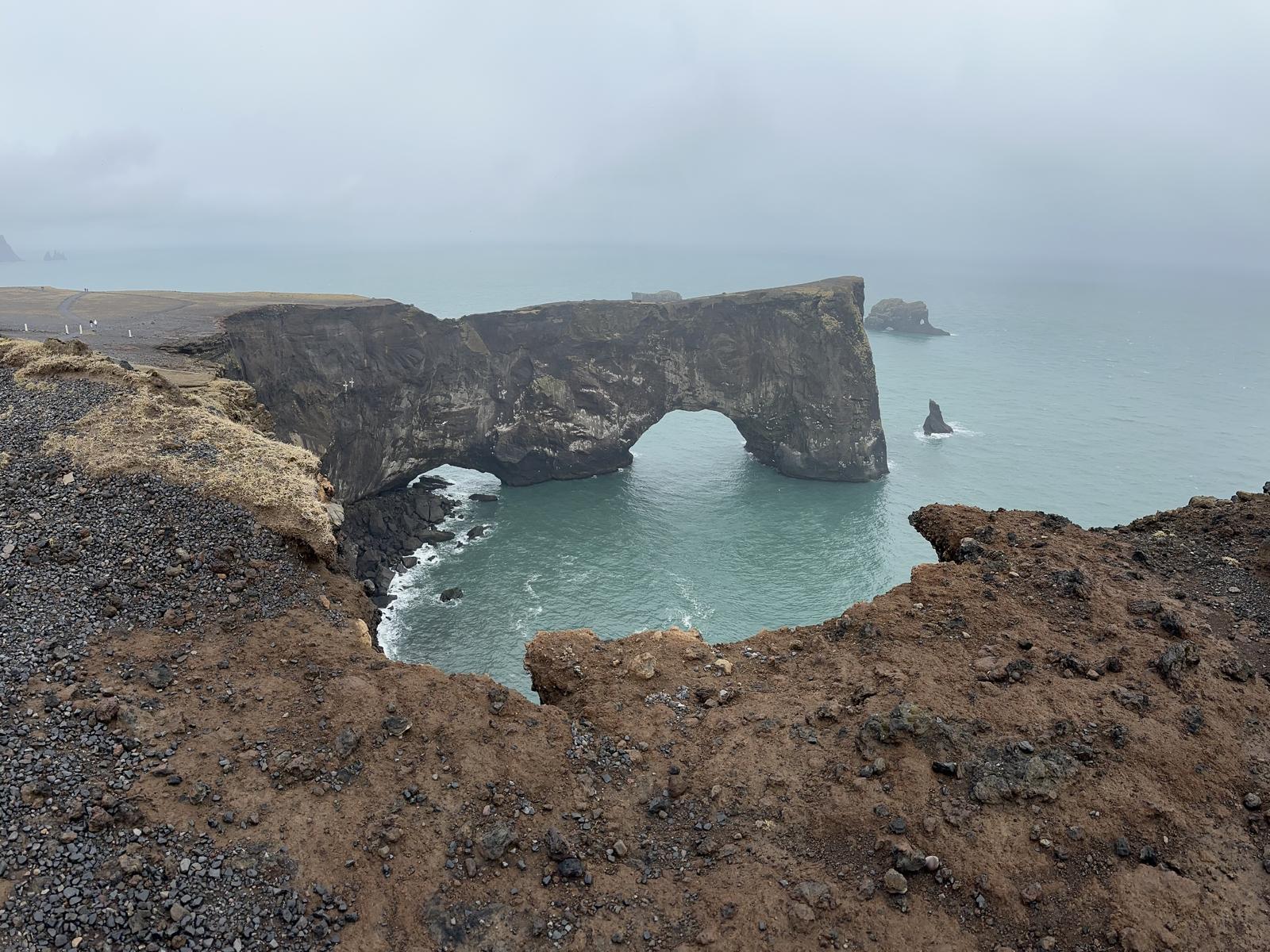 Arco natural de roca basáltica de Dyrhólaey con el Atlántico Norte al fondo en Islandia