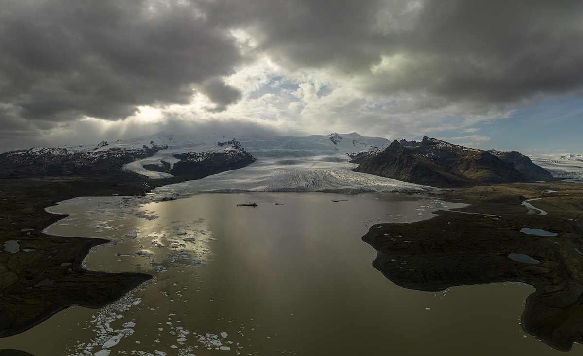 Vista aérea de la laguna glaciar de Fjallsárlón con agua oscura y el frente del glaciar Fjallsjökull en Islandia