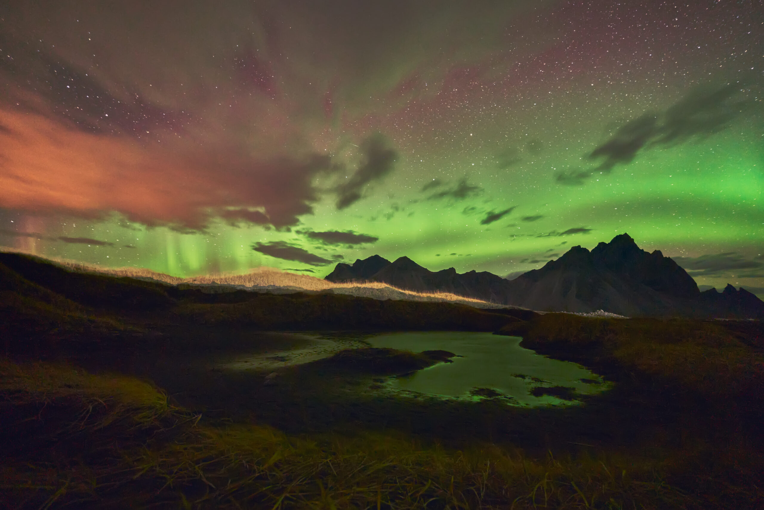 Auroras boreales sobre el Vestrahorn en Stokksnes de noche Auroras boreales sobre el Vestrahorn y su reflejo en la laguna de Stokksnes Islandia