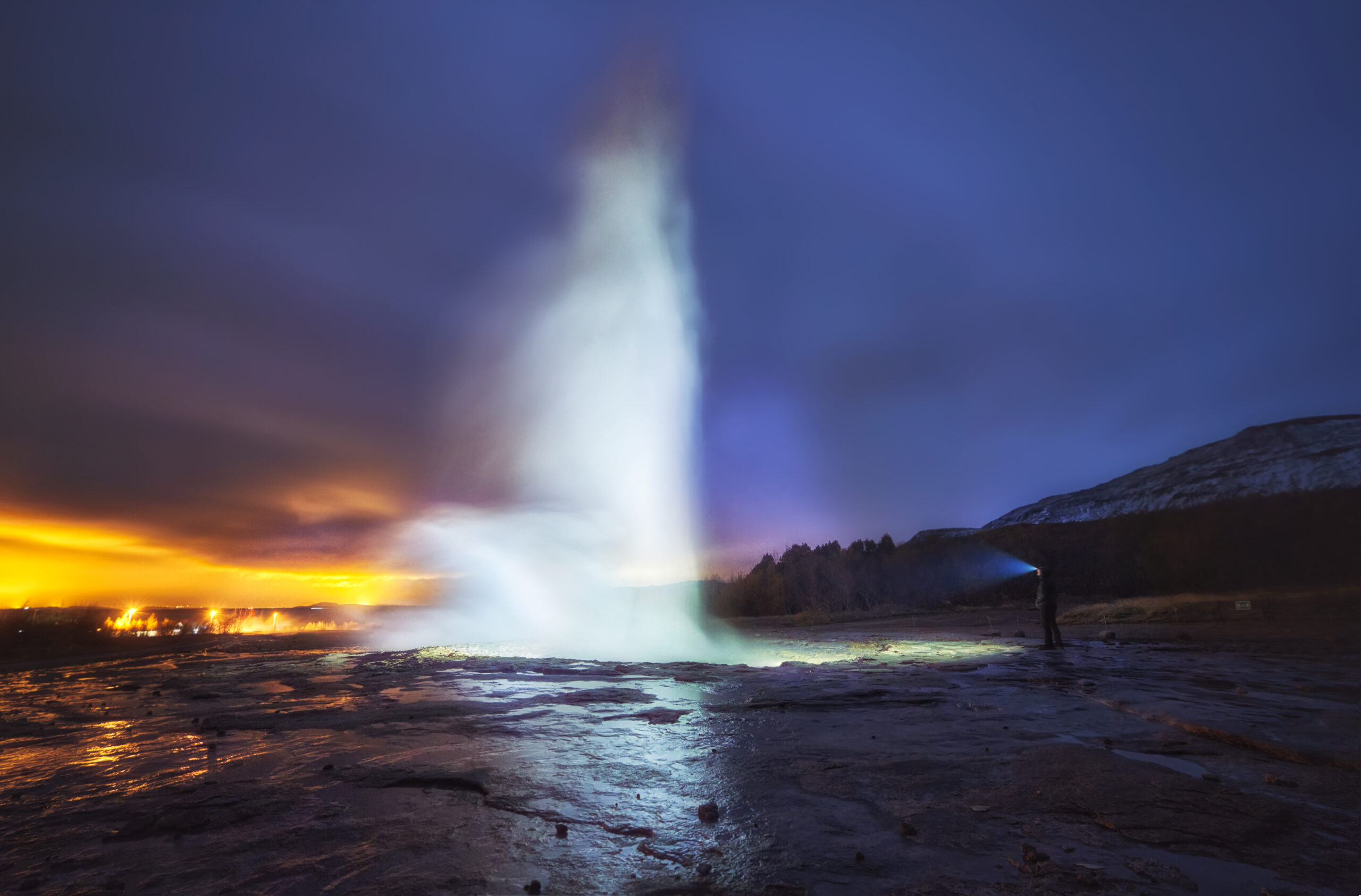 Erupción nocturna del géiser Strokkur iluminado en la zona geotérmica de Haukadalur