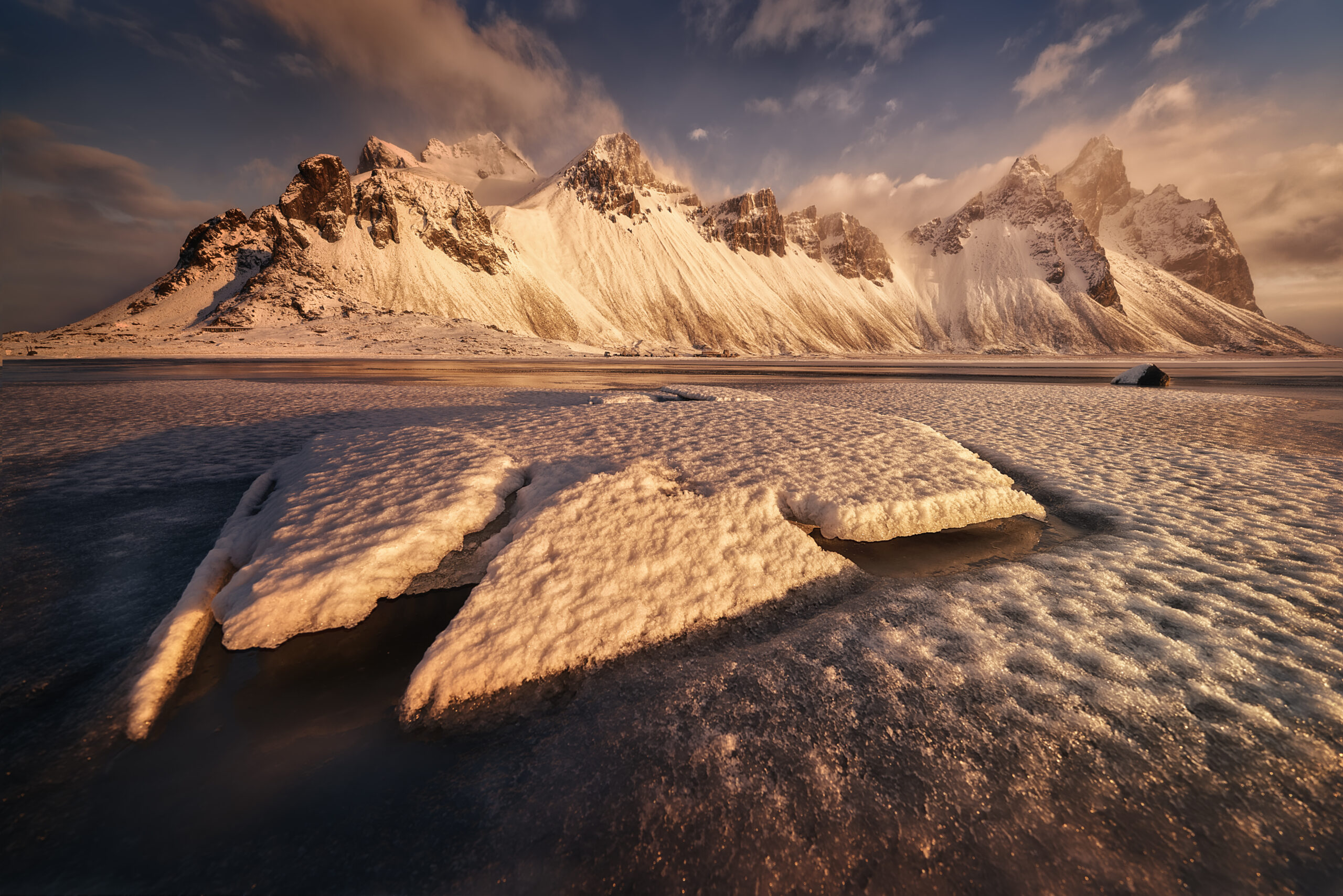 Vestrahorn nevado con luz dorada de invierno y hielo en primer plano en Stokksnes Vestrahorn nevado con luz dorada de invierno y placas de hielo en Stokksnes Islandia
